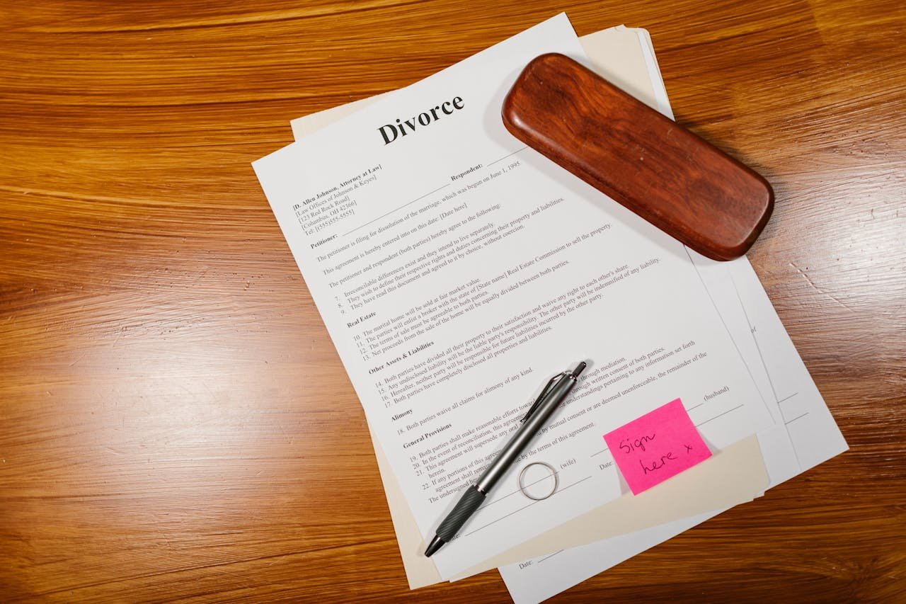 services-03 Flat lay of divorce papers with a pen and ring on a wooden table for legal themes.