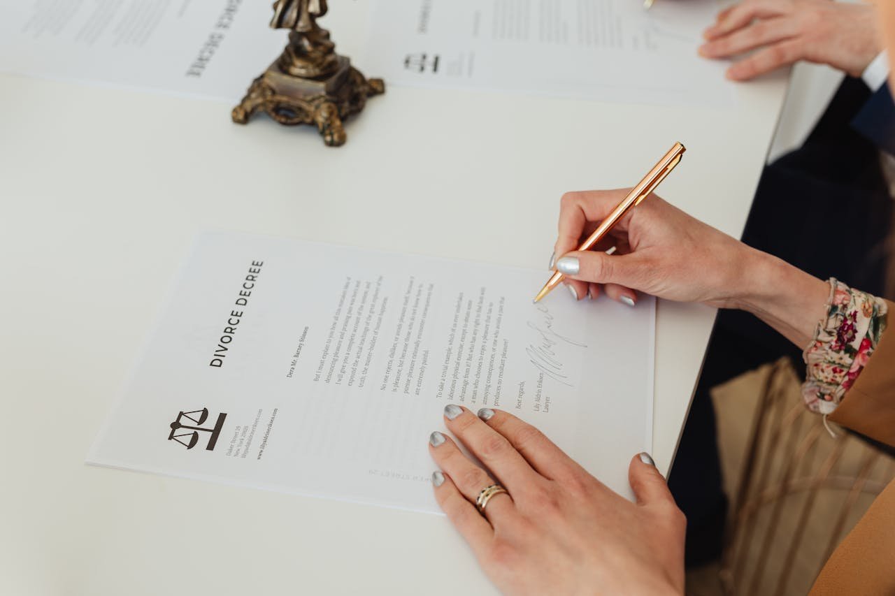services-02 Close-up of hands signing a divorce decree document on a desk, showcasing legal process.